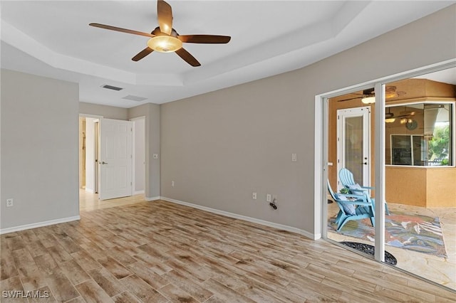 unfurnished room with a raised ceiling and light hardwood / wood-style flooring