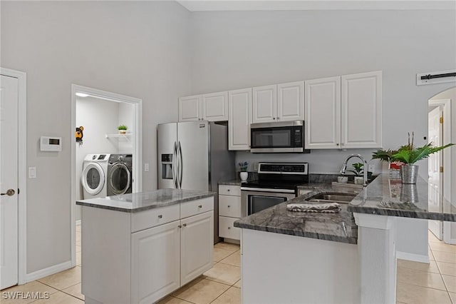 kitchen featuring appliances with stainless steel finishes, white cabinetry, sink, independent washer and dryer, and kitchen peninsula