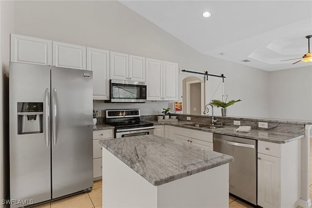 kitchen featuring sink, a center island, appliances with stainless steel finishes, kitchen peninsula, and a barn door