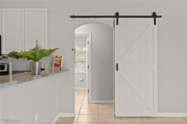 hall featuring a barn door and light tile patterned floors