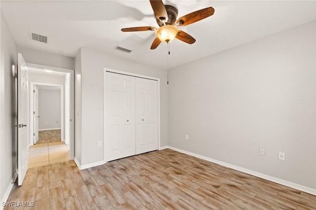 unfurnished bedroom with ceiling fan, light wood-type flooring, and a closet