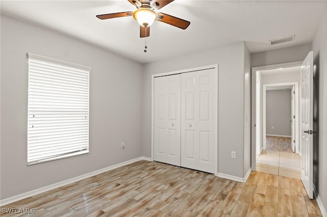 unfurnished bedroom with light hardwood / wood-style flooring, a closet, and ceiling fan