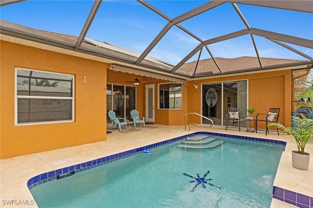 view of pool with a patio area, ceiling fan, and glass enclosure