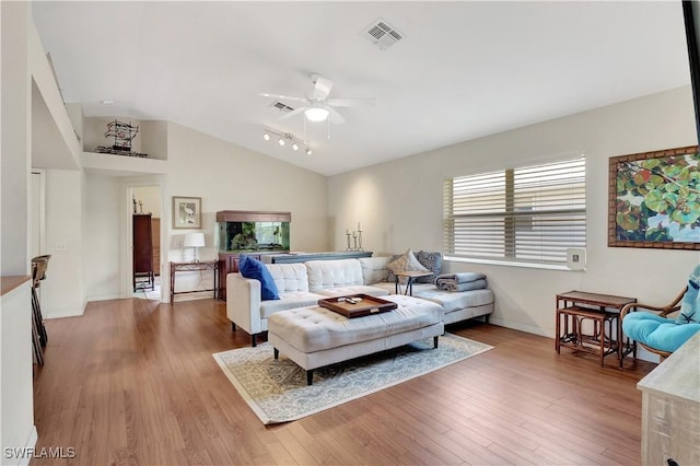 living room with lofted ceiling, visible vents, and wood finished floors