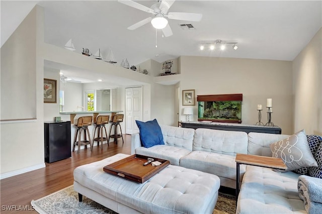 living room featuring visible vents, a ceiling fan, vaulted ceiling, wood finished floors, and baseboards