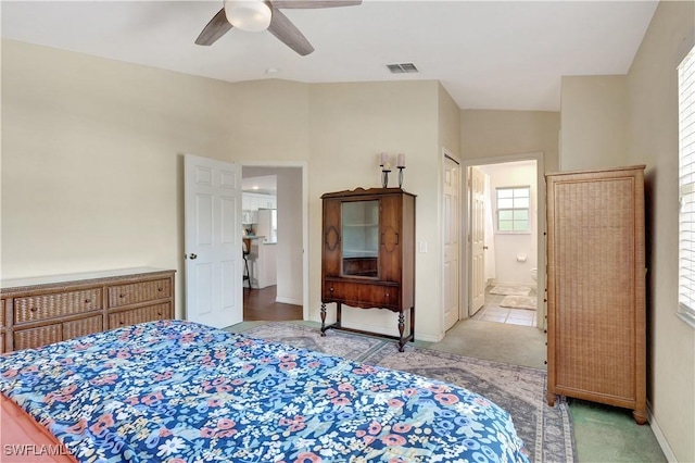 bedroom with baseboards, connected bathroom, visible vents, and a ceiling fan