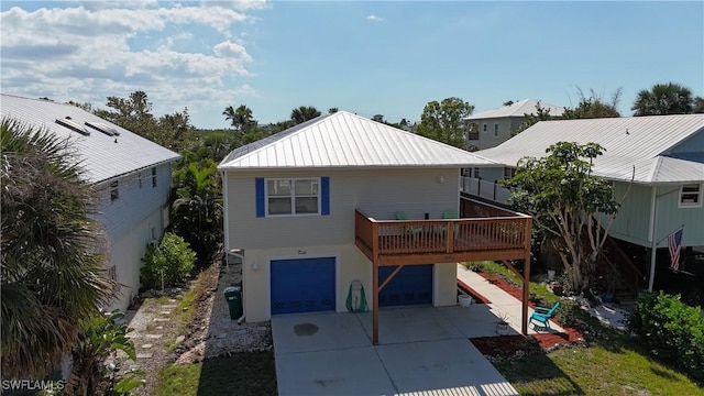 back of property featuring an attached garage, metal roof, concrete driveway, and a wooden deck