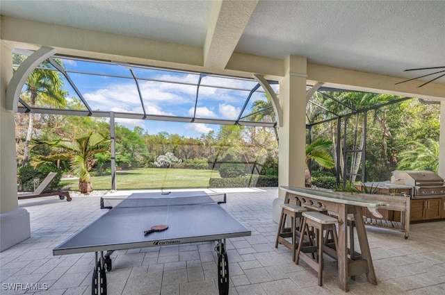 view of patio / terrace with an outdoor kitchen, area for grilling, ceiling fan, and a lanai