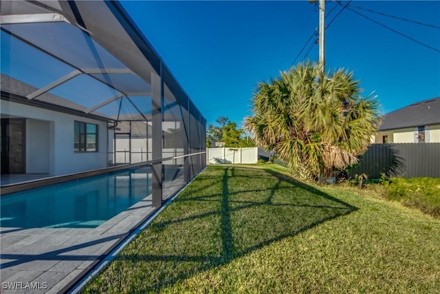 view of swimming pool featuring a yard and glass enclosure