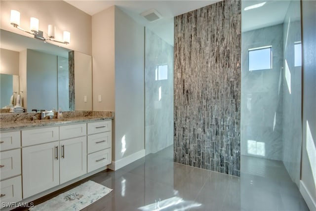 bathroom featuring tile patterned flooring, vanity, and tiled shower