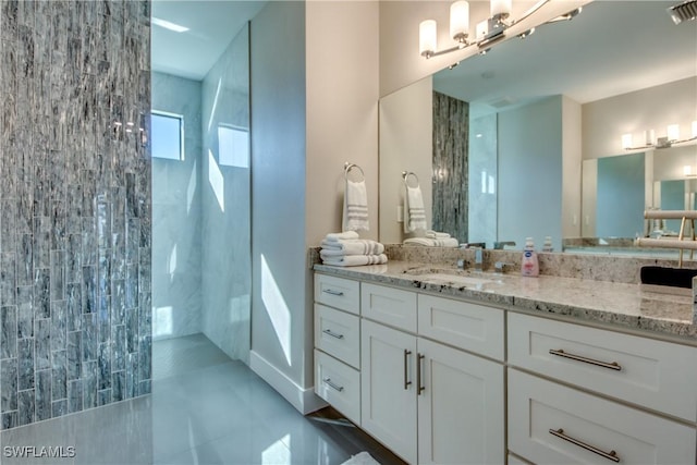 bathroom with tiled shower, vanity, and tile patterned floors