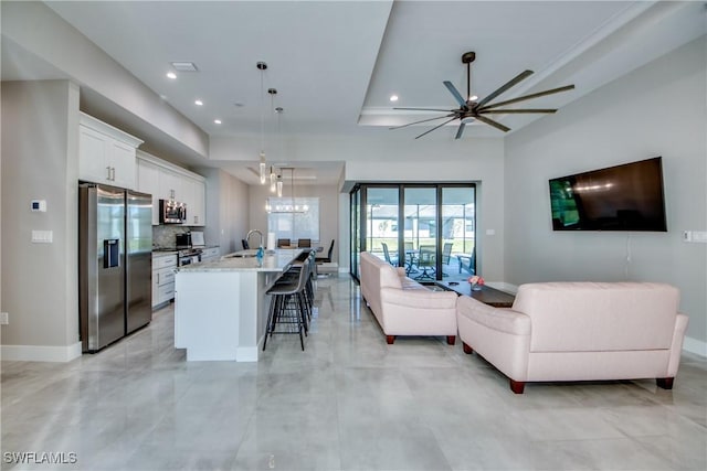 living room with sink, a chandelier, and a tray ceiling