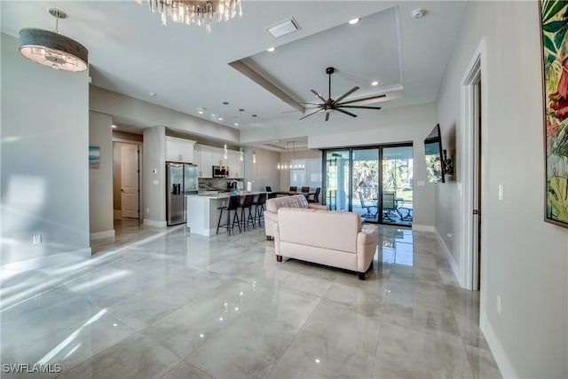 living room with a tray ceiling and ceiling fan