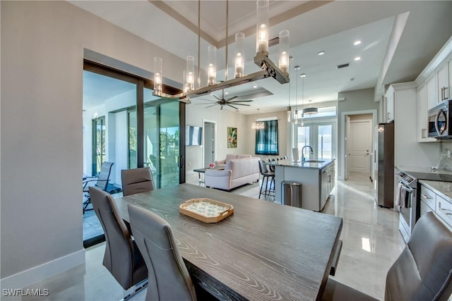 dining area featuring a tray ceiling, sink, and french doors