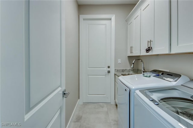 laundry area featuring light tile patterned flooring, cabinets, sink, and washer and dryer