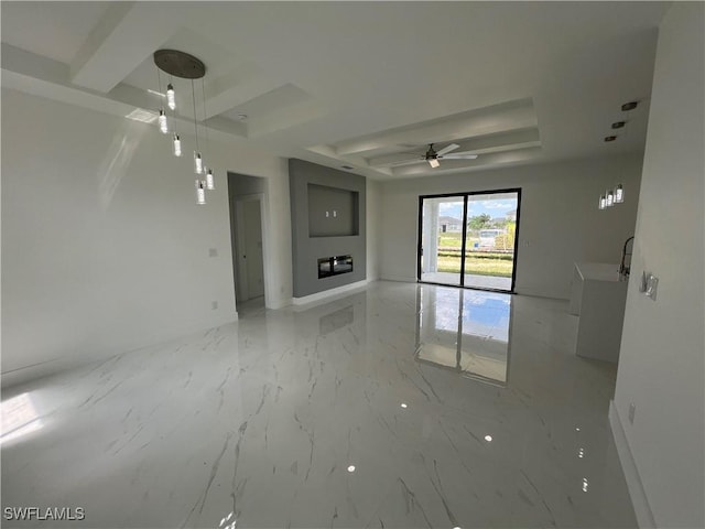 unfurnished living room featuring ceiling fan and a raised ceiling