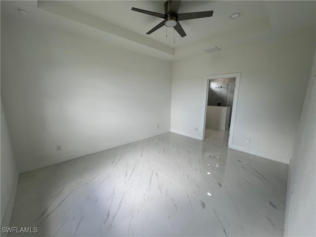 spare room with ceiling fan and a tray ceiling