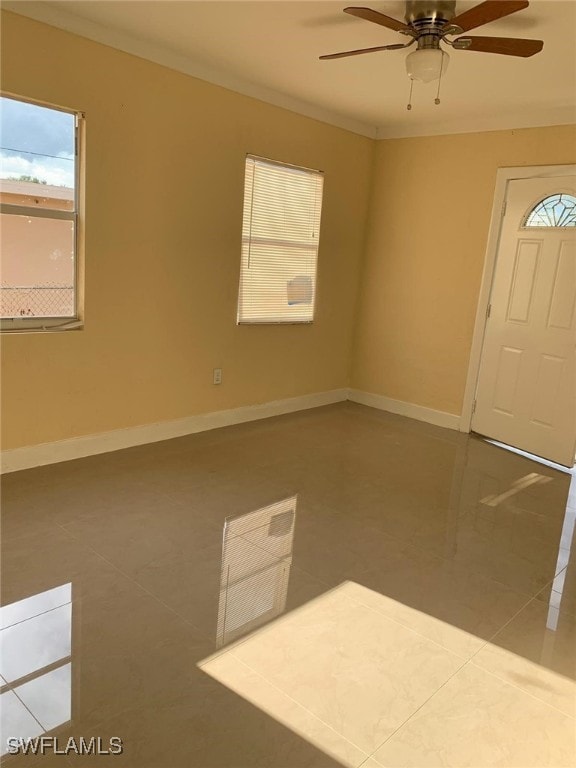 tiled entrance foyer with ornamental molding and ceiling fan