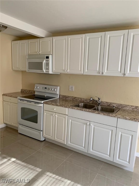 kitchen with white cabinetry, sink, light tile patterned flooring, and white appliances