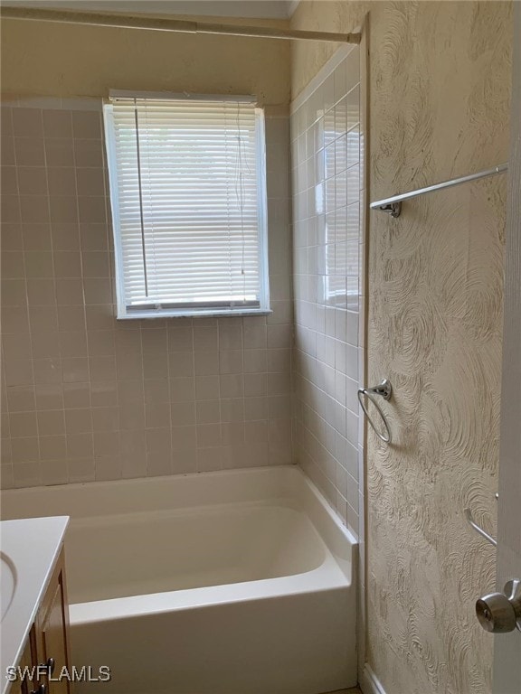 bathroom featuring tiled shower / bath and vanity