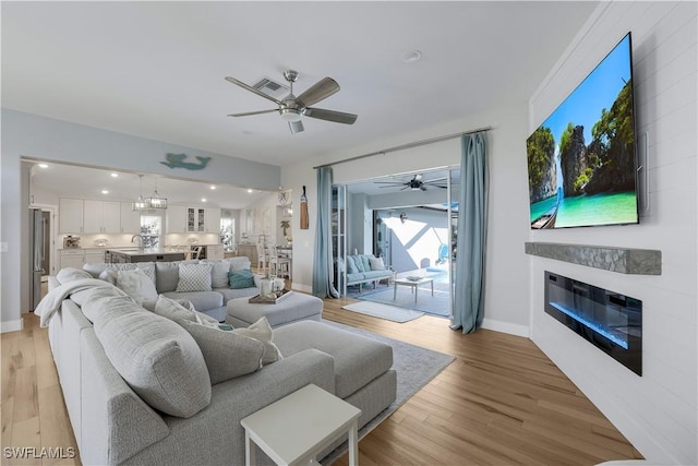 living room with sink, light hardwood / wood-style floors, and ceiling fan