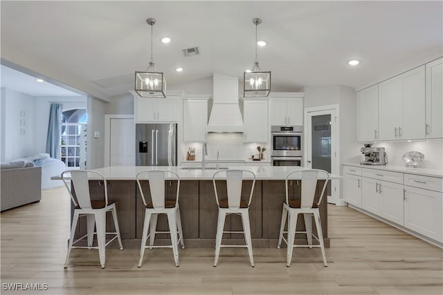 kitchen featuring pendant lighting, premium range hood, a spacious island, and appliances with stainless steel finishes