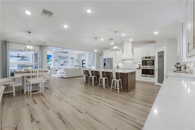 kitchen featuring decorative light fixtures, stainless steel appliances, a center island, and white cabinets