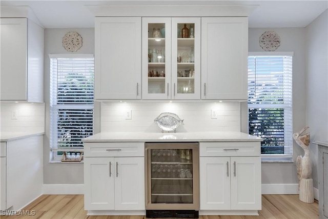 bar featuring a healthy amount of sunlight, beverage cooler, and white cabinets