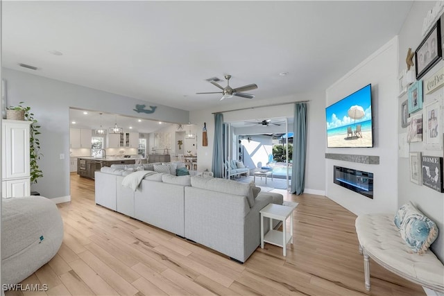 living room featuring sink, light hardwood / wood-style flooring, and ceiling fan