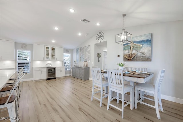 dining space with wine cooler, vaulted ceiling, a healthy amount of sunlight, and light wood-type flooring