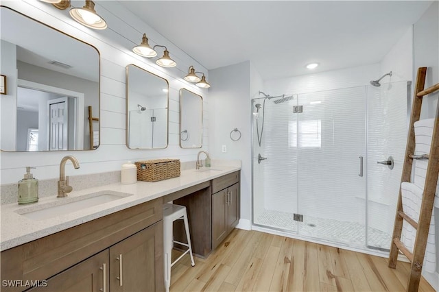 bathroom with wood-type flooring, vanity, and a shower with shower door