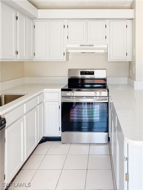 kitchen featuring stainless steel electric range, white cabinets, and light tile patterned flooring