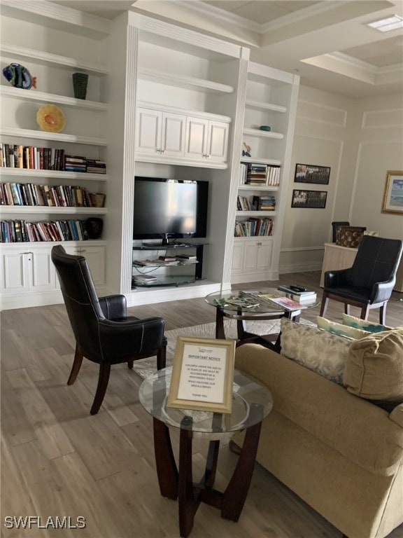 living room featuring built in shelves, ornamental molding, and wood-type flooring