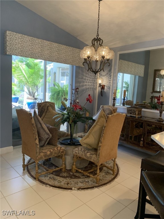 tiled dining space with an inviting chandelier and lofted ceiling