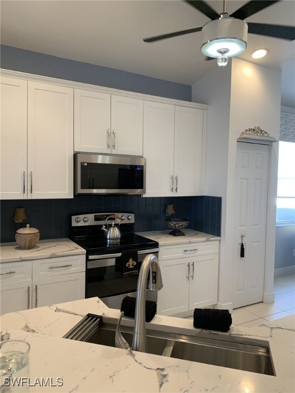 kitchen featuring white cabinetry, appliances with stainless steel finishes, backsplash, and light stone counters