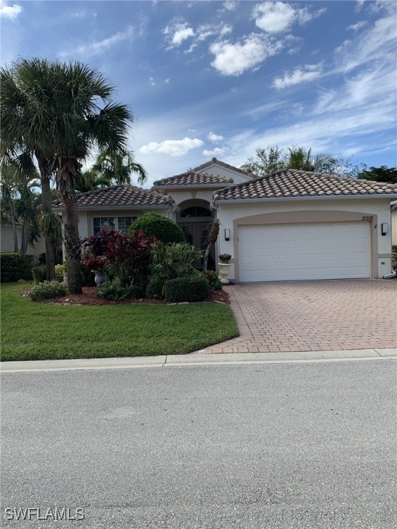 mediterranean / spanish-style home featuring a garage and a front yard