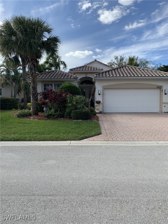 mediterranean / spanish house featuring a garage and a front lawn