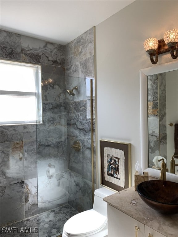 bathroom featuring vanity, a tile shower, and toilet