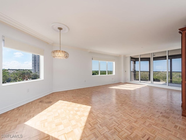 empty room featuring crown molding, light parquet flooring, and a notable chandelier