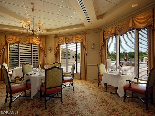 carpeted dining space featuring an inviting chandelier and a tray ceiling