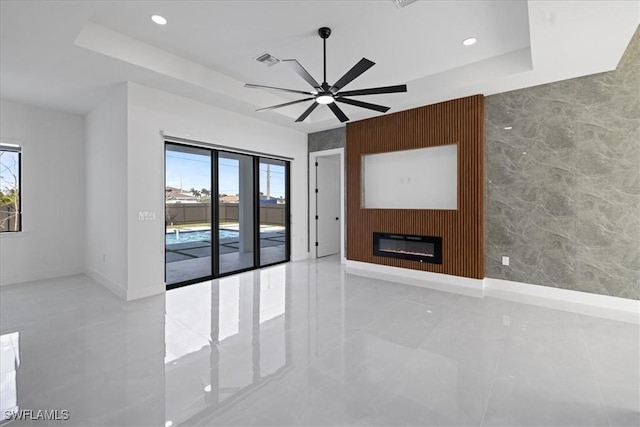 spare room with a wealth of natural light, ceiling fan, and a tray ceiling