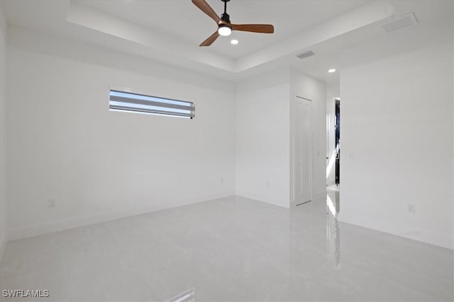 empty room featuring a raised ceiling and ceiling fan