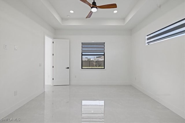 spare room with ceiling fan and a tray ceiling