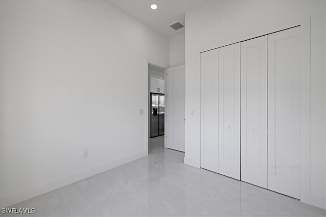 unfurnished bedroom with a closet and stainless steel refrigerator with ice dispenser