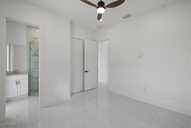 unfurnished bedroom featuring ensuite bathroom, sink, ceiling fan, and a closet