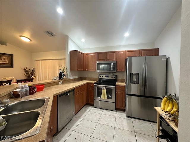 kitchen featuring sink, light tile patterned floors, stainless steel appliances, and kitchen peninsula