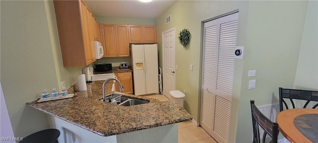 kitchen featuring sink, dark stone countertops, white appliances, and kitchen peninsula