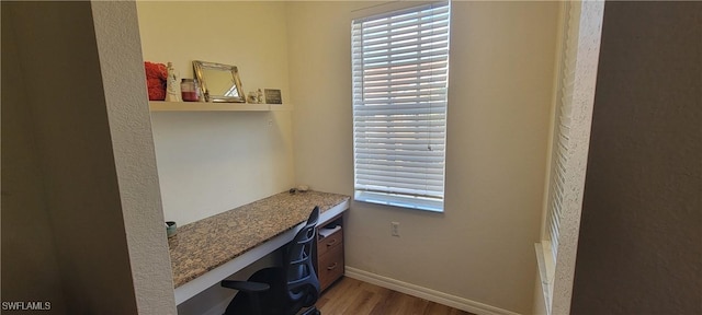 office area with a healthy amount of sunlight, built in study area, baseboards, and wood finished floors