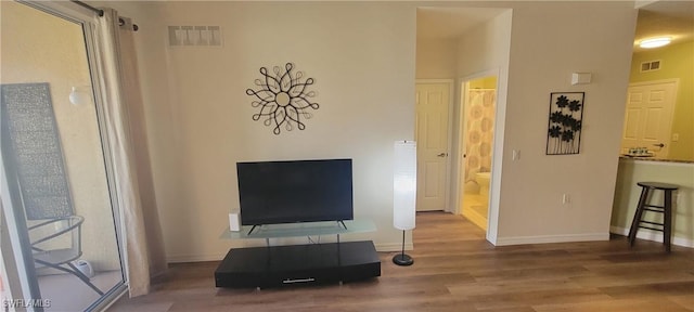 living area with visible vents, baseboards, and wood finished floors