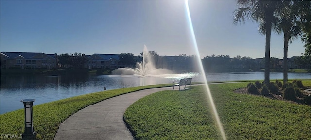 surrounding community featuring a water view and a lawn